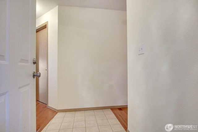 corridor with light wood-type flooring and baseboards