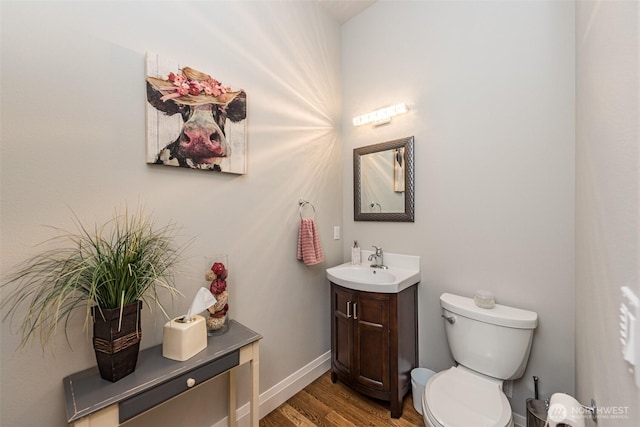 bathroom featuring toilet, vanity, baseboards, and wood finished floors