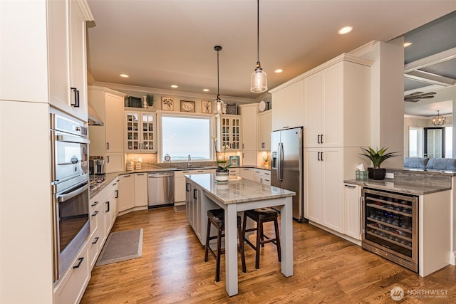 kitchen featuring light stone countertops, wine cooler, glass insert cabinets, appliances with stainless steel finishes, and a kitchen breakfast bar