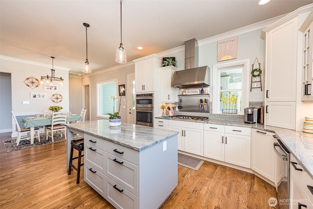 kitchen featuring white cabinets, appliances with stainless steel finishes, light wood-type flooring, and wall chimney range hood