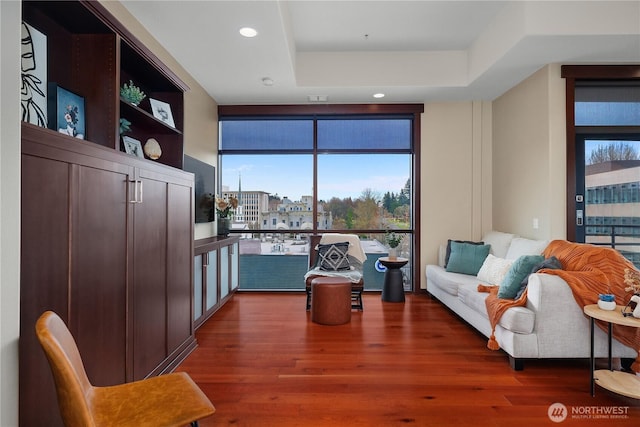 sitting room with recessed lighting, floor to ceiling windows, a raised ceiling, and wood finished floors