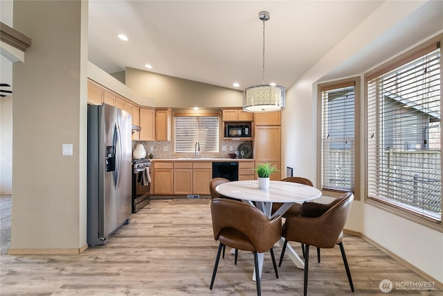 kitchen with light brown cabinets, lofted ceiling, a sink, black appliances, and tasteful backsplash