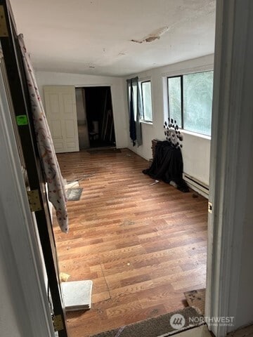 hall with light wood finished floors and a baseboard radiator