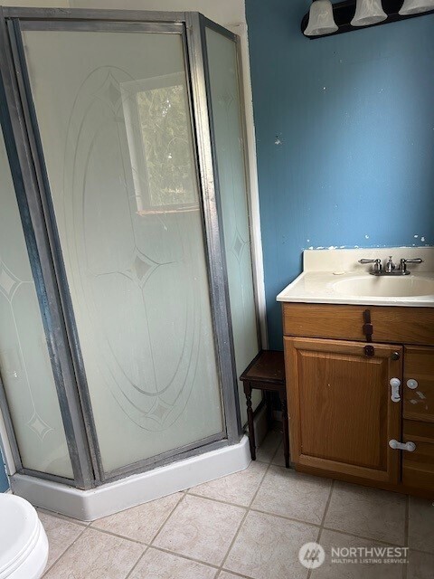 full bath featuring vanity, tile patterned floors, and a stall shower