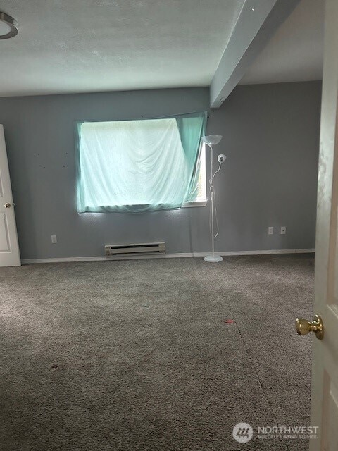 unfurnished room with a baseboard radiator, baseboards, and beamed ceiling