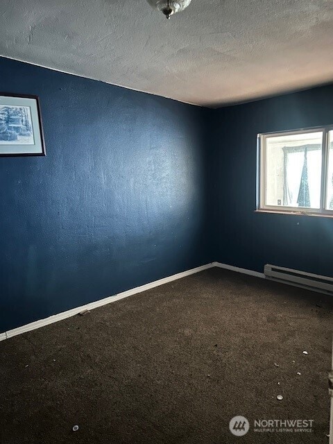 unfurnished room featuring baseboards, carpet, baseboard heating, and a textured ceiling