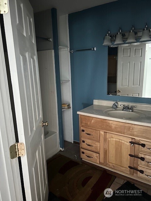 full bath featuring washtub / shower combination, vanity, and tile patterned flooring