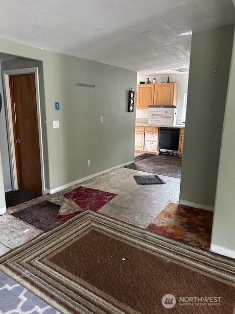 unfurnished living room with a textured ceiling and baseboards