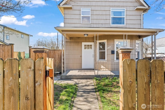 view of front of home featuring a porch, fence, and a gate