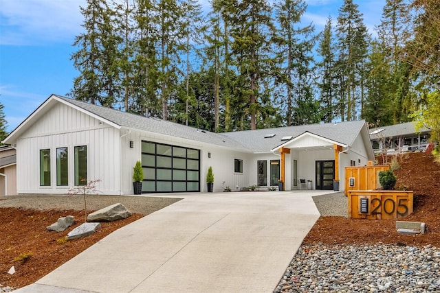 modern farmhouse featuring an attached garage, board and batten siding, driveway, and a shingled roof