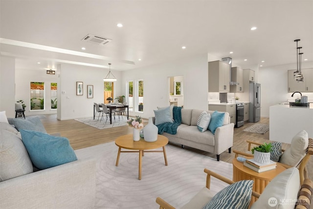 living area with visible vents, recessed lighting, light wood-type flooring, and baseboards