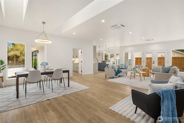 living area featuring light wood-type flooring, visible vents, and a healthy amount of sunlight