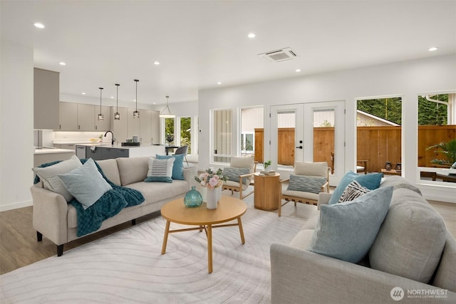 living area with recessed lighting, visible vents, light wood-style flooring, and french doors