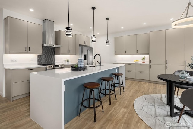 kitchen with stainless steel appliances, gray cabinets, and wall chimney range hood