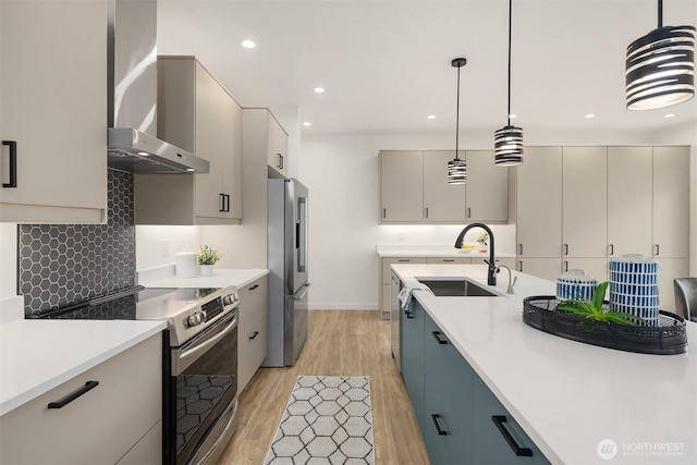 kitchen with wall chimney range hood, light countertops, electric range oven, freestanding refrigerator, and a sink