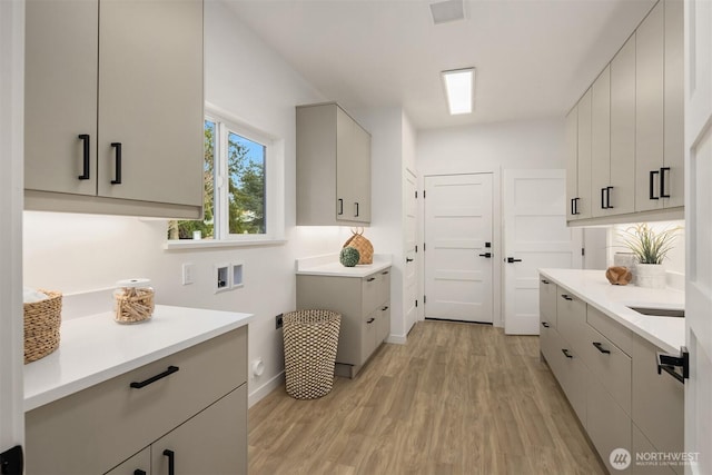 washroom with visible vents, baseboards, light wood-type flooring, hookup for a washing machine, and cabinet space