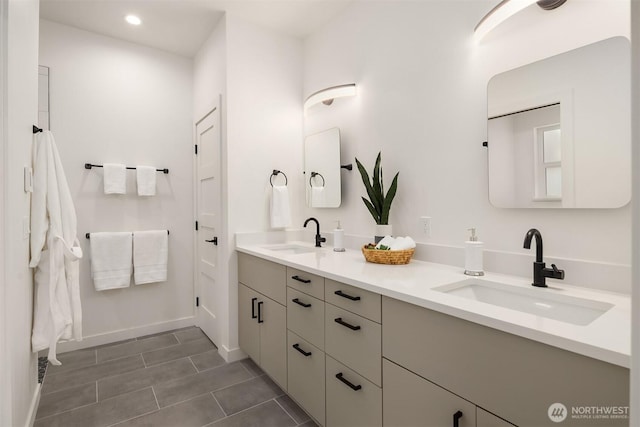 bathroom with double vanity, recessed lighting, baseboards, and a sink