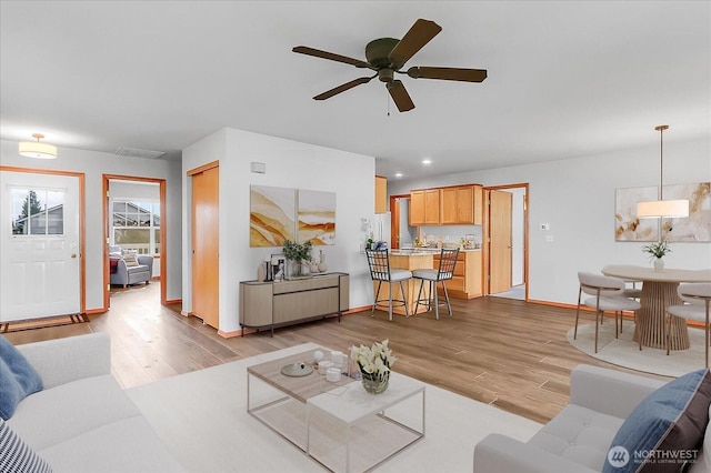 living area with a ceiling fan, light wood-style flooring, recessed lighting, and baseboards