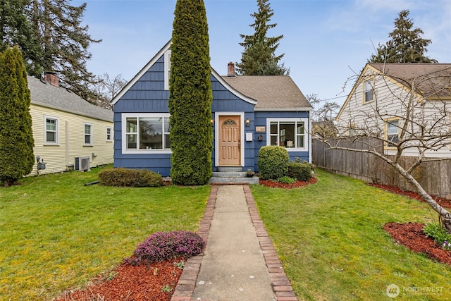 bungalow-style house featuring cooling unit, roof with shingles, a front lawn, and fence