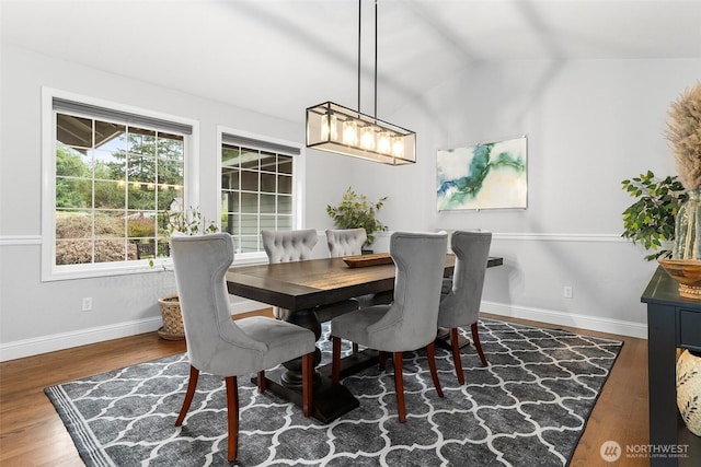 dining area featuring vaulted ceiling, baseboards, and wood finished floors