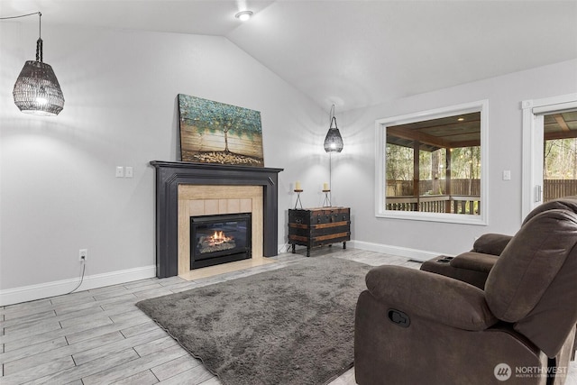 living room featuring a fireplace, wood finished floors, baseboards, and vaulted ceiling