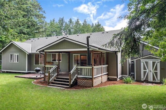 back of house featuring a lawn, a shingled roof, a storage shed, and an outdoor structure