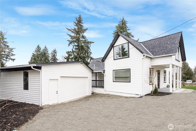 view of front of house with a shingled roof and gravel driveway