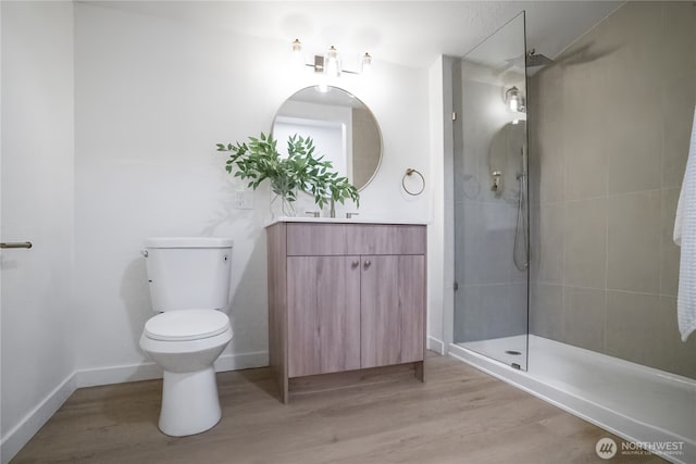 bathroom with toilet, wood finished floors, and tiled shower