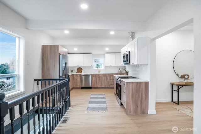 kitchen featuring light countertops, stainless steel appliances, light wood-style floors, white cabinetry, and a sink