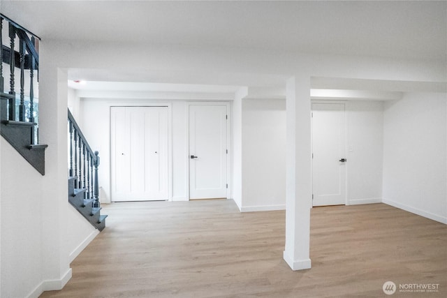 finished basement with stairway, wood finished floors, and baseboards