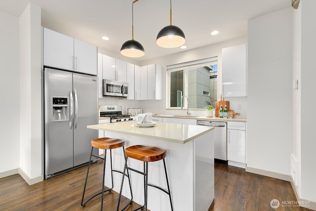 kitchen featuring a sink, white cabinets, a breakfast bar area, and stainless steel appliances