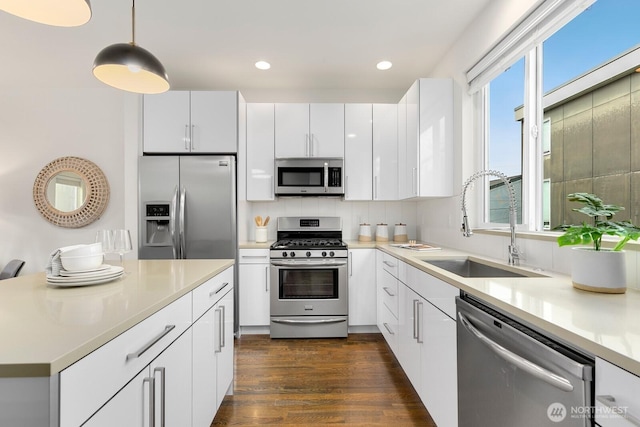 kitchen featuring a sink, stainless steel appliances, dark wood-style flooring, and white cabinetry