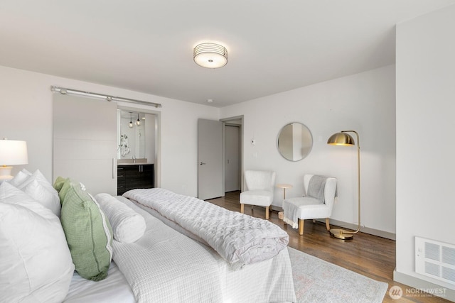 bedroom featuring visible vents, ensuite bath, and wood finished floors