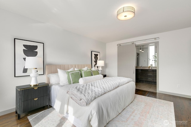 bedroom with wood finished floors, baseboards, and connected bathroom