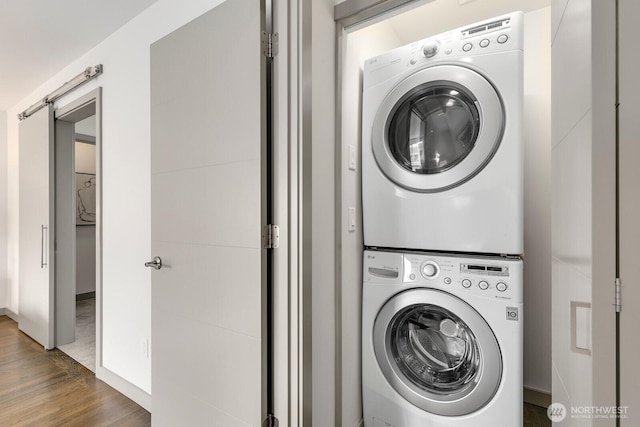 laundry area featuring stacked washer / dryer, laundry area, and wood finished floors