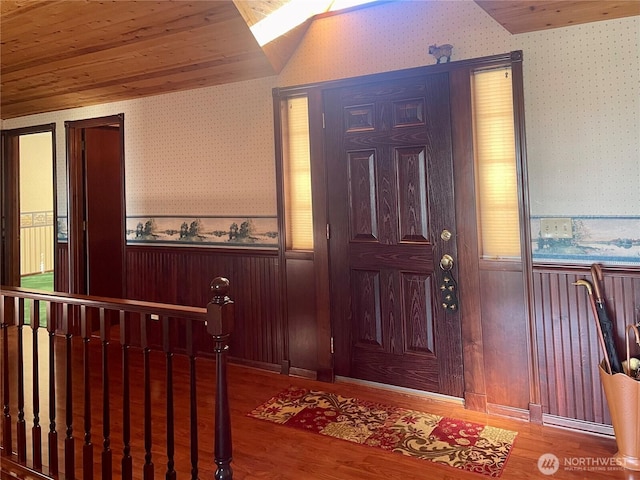 foyer entrance with wood ceiling, wood finished floors, wainscoting, and wallpapered walls