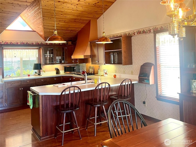 kitchen with premium range hood, stainless steel microwave, wallpapered walls, wooden ceiling, and light countertops