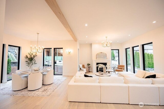 living area featuring beam ceiling, light wood-style flooring, recessed lighting, a fireplace, and a chandelier