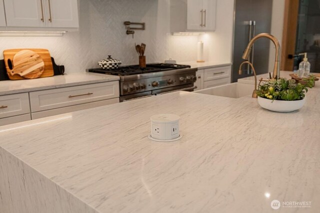 kitchen featuring light stone counters, white cabinets, and high end stainless steel range oven