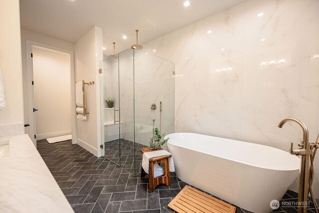 bathroom with recessed lighting, a soaking tub, tile walls, and a shower stall