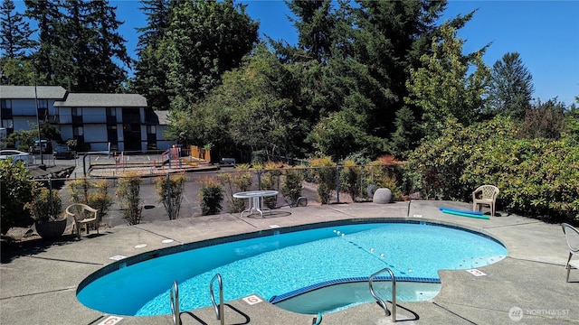 view of swimming pool featuring a patio area, a pool with connected hot tub, and fence