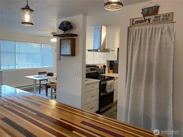 kitchen featuring double oven range, a textured ceiling, white cabinetry, wall chimney exhaust hood, and light countertops