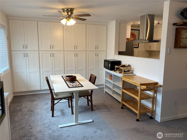 dining room featuring ceiling fan, a textured ceiling, baseboards, and dark colored carpet