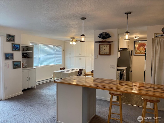 kitchen featuring dark colored carpet, a baseboard radiator, wooden counters, and freestanding refrigerator