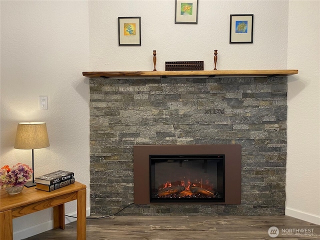 room details with baseboards, wood finished floors, and a glass covered fireplace