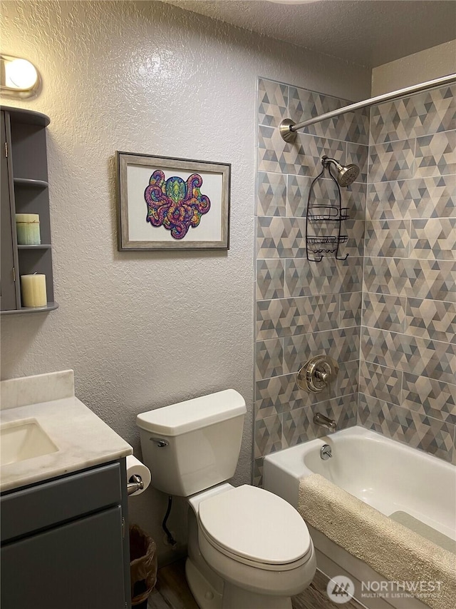 full bathroom featuring vanity, washtub / shower combination, a textured ceiling, toilet, and a textured wall