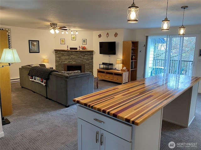 kitchen with wood counters, a baseboard heating unit, open floor plan, a fireplace, and dark colored carpet