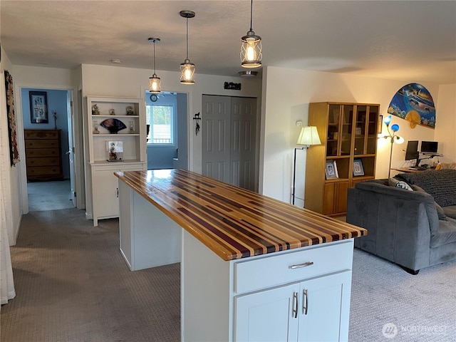 kitchen featuring a center island, open floor plan, butcher block counters, carpet flooring, and white cabinetry