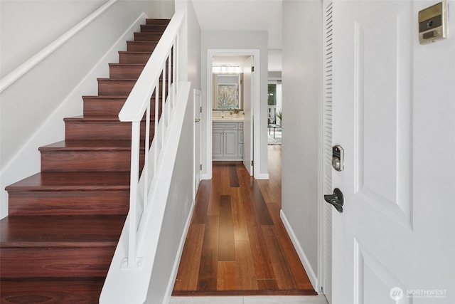 foyer entrance featuring dark wood-style floors, stairs, and baseboards