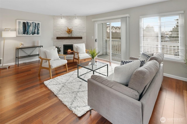 living area with a fireplace, baseboards, and wood finished floors